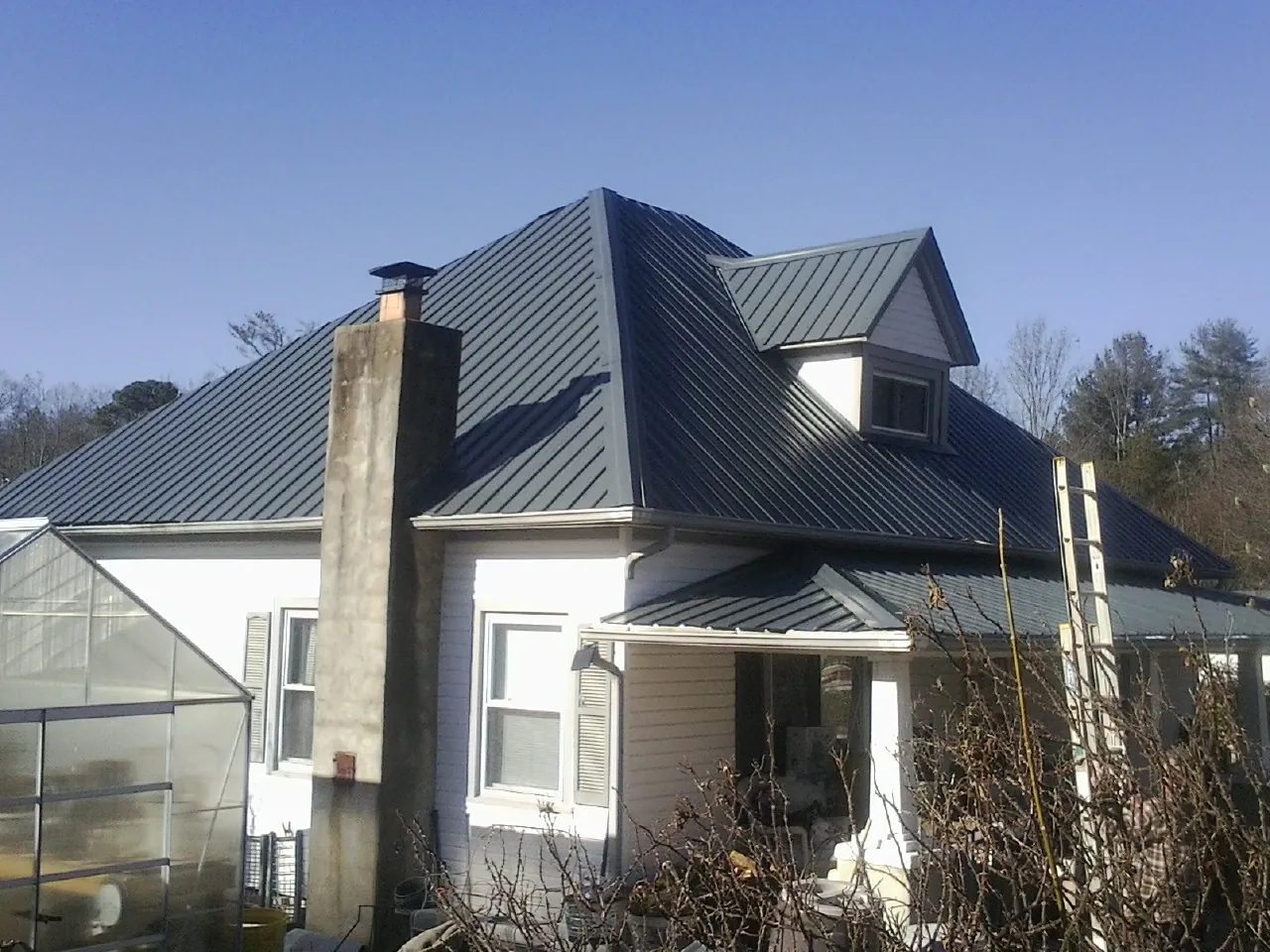 Dark blue standing seam metal roof on a white farmhouse with dormer — Slate & Tile Roof Repair by Roofing Brothers in Alverton