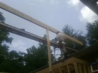 Carpenter setting a ridge beam over a new addition frame — Ice Dam Removal by Roofing Brothers in Alverton