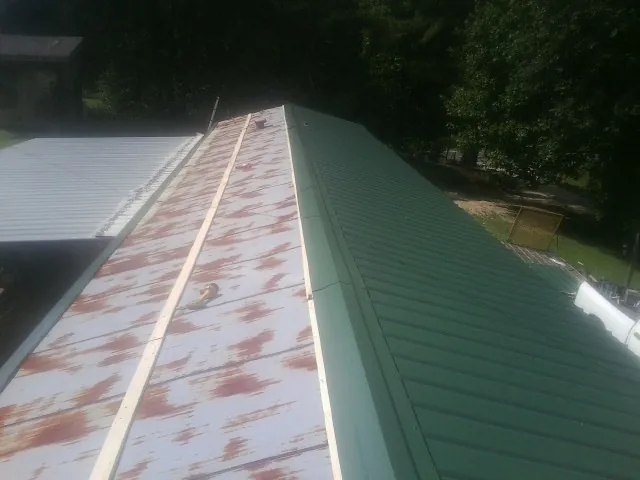 Old rusted panels beside newly installed green metal roofing — Wind Damage Roof Repair by Roofing Brothers in Alverton