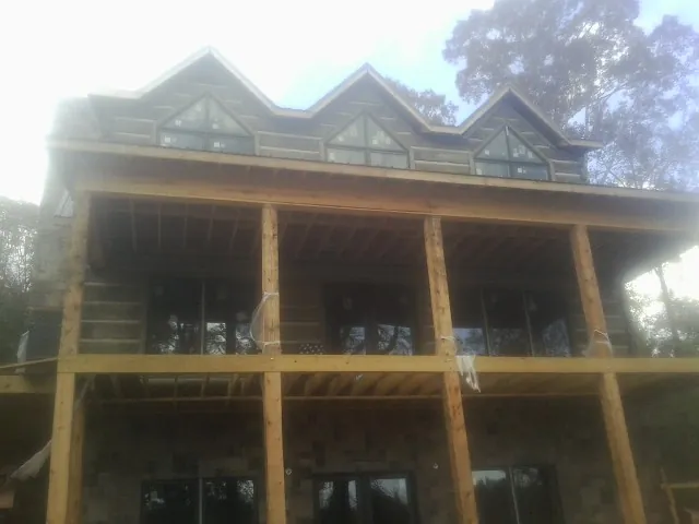 Dormers and porch framing on a large log home under construction — Roof Coating work by our crew in Alverton