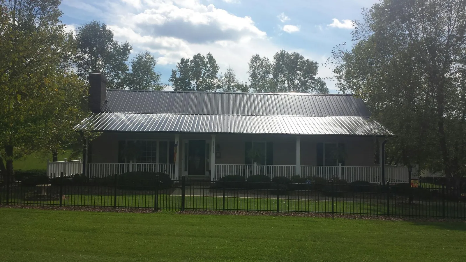 Gray metal roof on a brick ranch with a full width front porch — Gutter Guard Installation work by our crew in Alverton