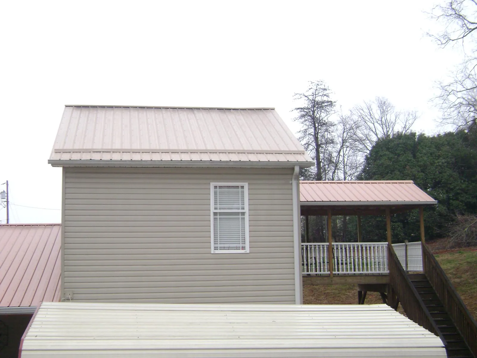 Tan metal roofs on a two story addition and attached porch, from a Roof Replacement job in Alverton